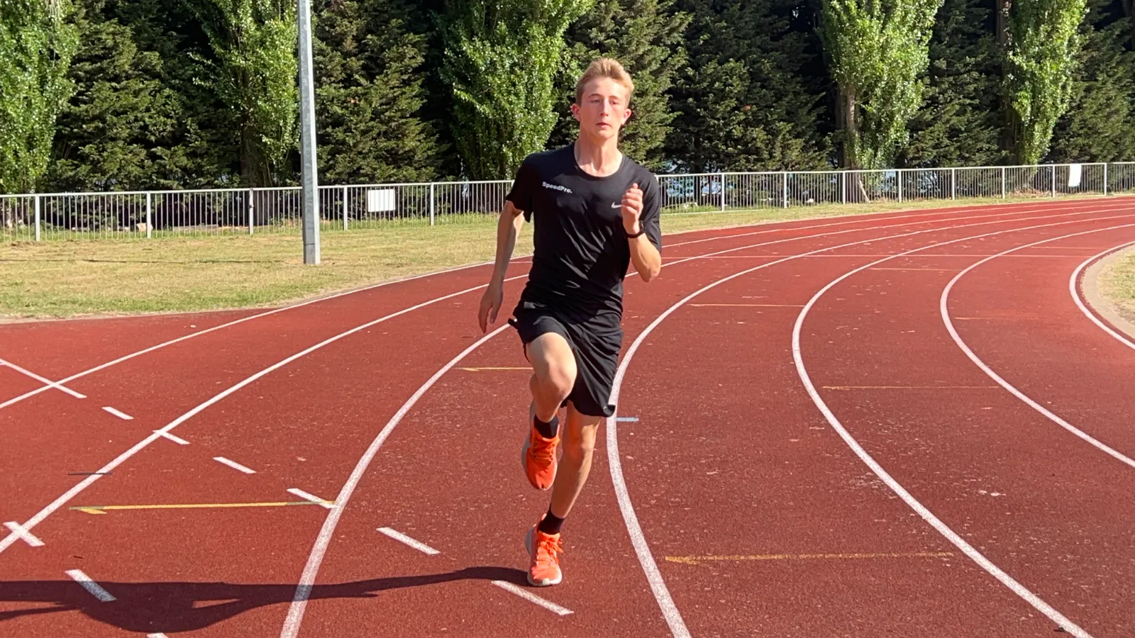 SpeedPro athlete in club training kit running the bend at a SpeedPro session