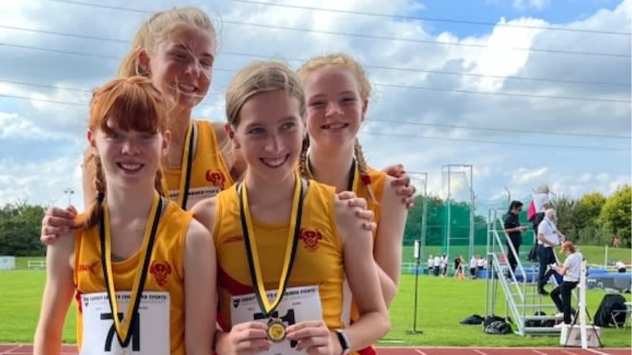 Four SpeedPro athletes in their club vests with their relay medals at the Surrey County Championships
