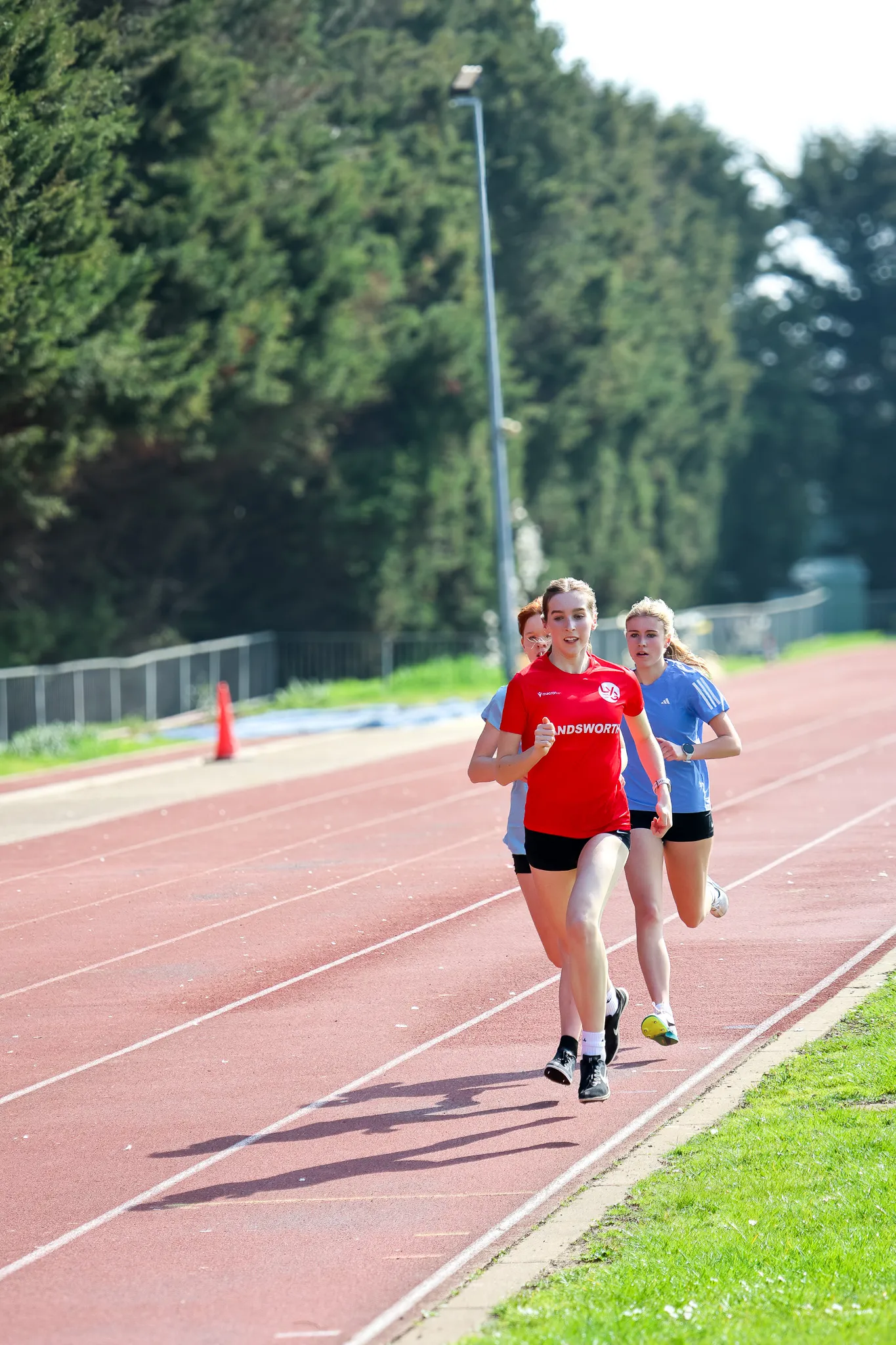 Three SpeedPro middle-distance athletes running a rep together during a training session on the track